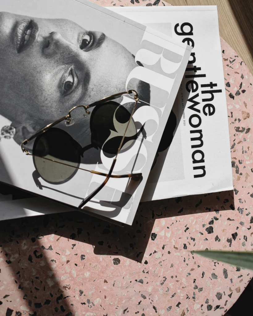 Zwei Modemagazine mit Sonnenbrille auf rosa Terrazzo – symbolisiert Medienplatzierungen durch PR für Unternehmerinnen